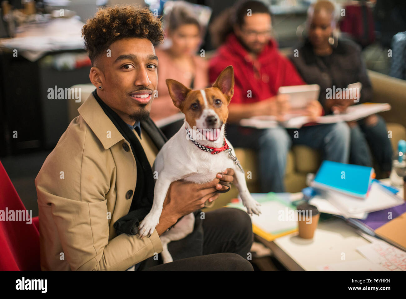 Portrait smiling creative businessman with dog in office Banque D'Images
