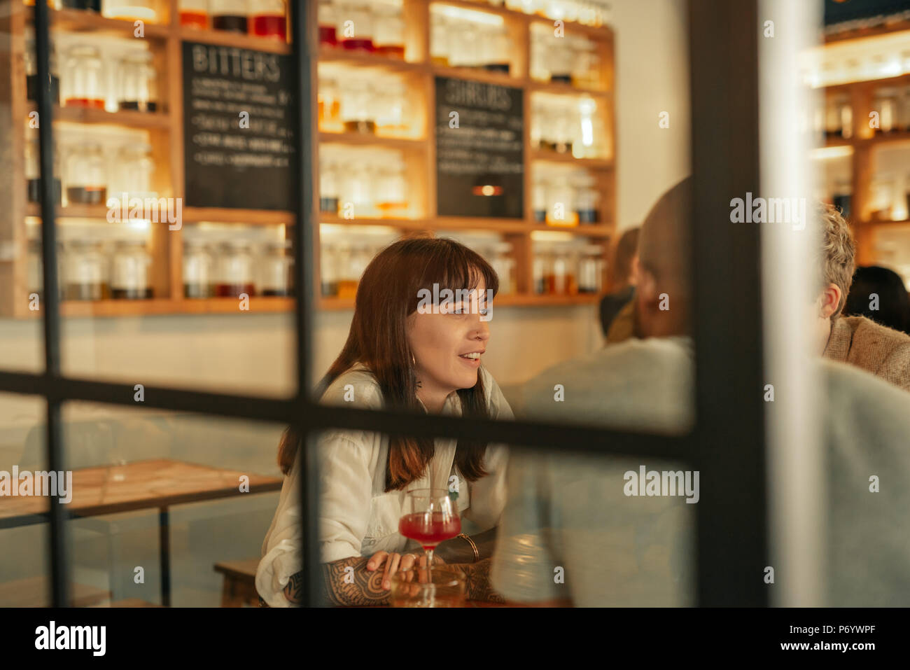 Jeune femme parlant avec des amis autour d'un verre dans un bar Banque D'Images
