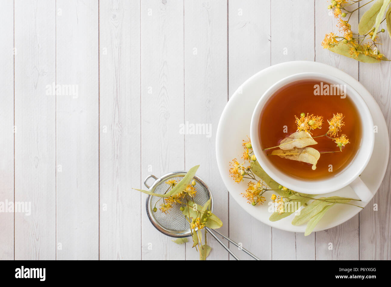 Tasse de thé avec des fleurs de tilleul sur une table lumineuse. Banque D'Images