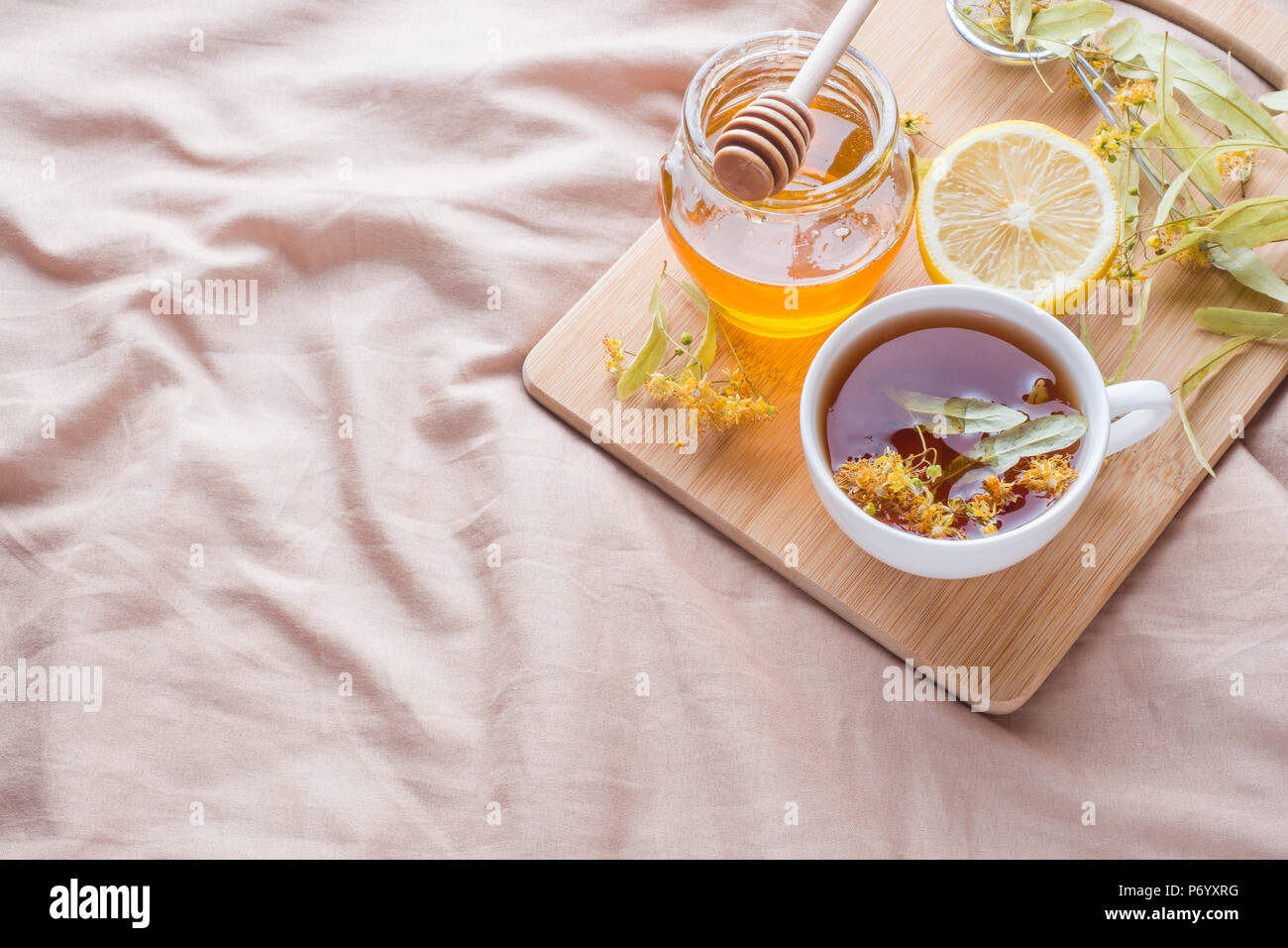 Plateau avec Linden, miel et citron. Le plateau sur le lit, le concept de la traitement du rhume. Banque D'Images