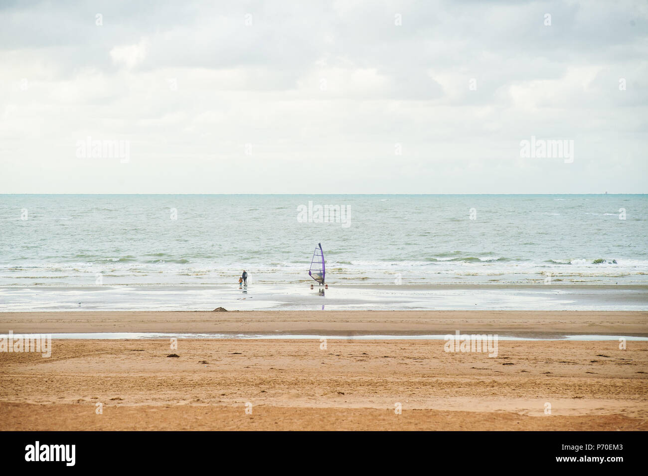 Le surf sur la plage en face de vagues à l'automne avec certains personnes marchant par Banque D'Images