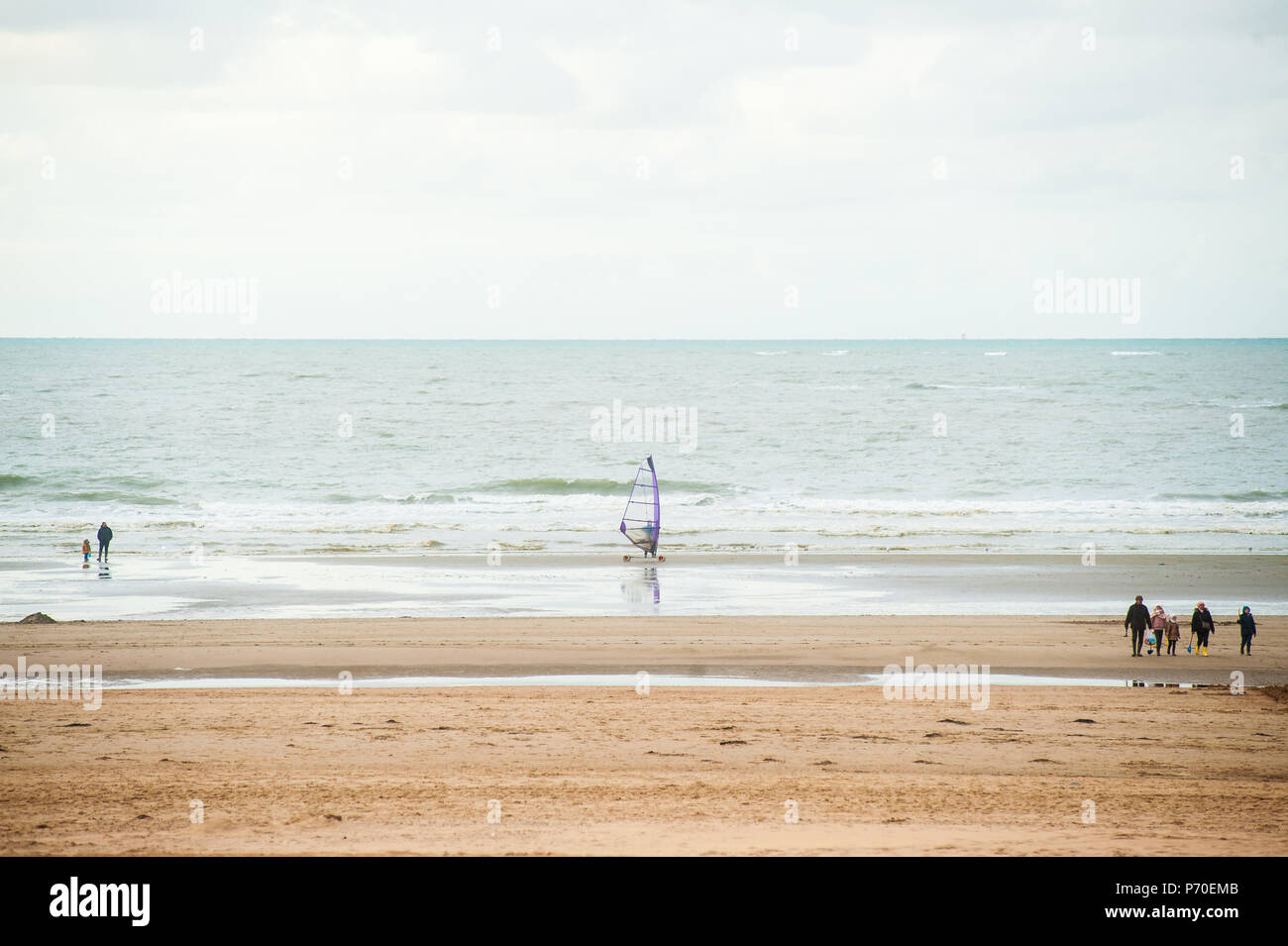 Le surf sur la plage en face de vagues à l'automne avec certains personnes marchant par Banque D'Images