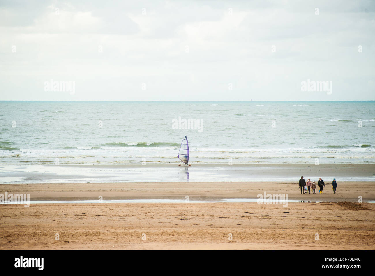 Le surf sur la plage en face de vagues à l'automne avec certains personnes marchant par Banque D'Images