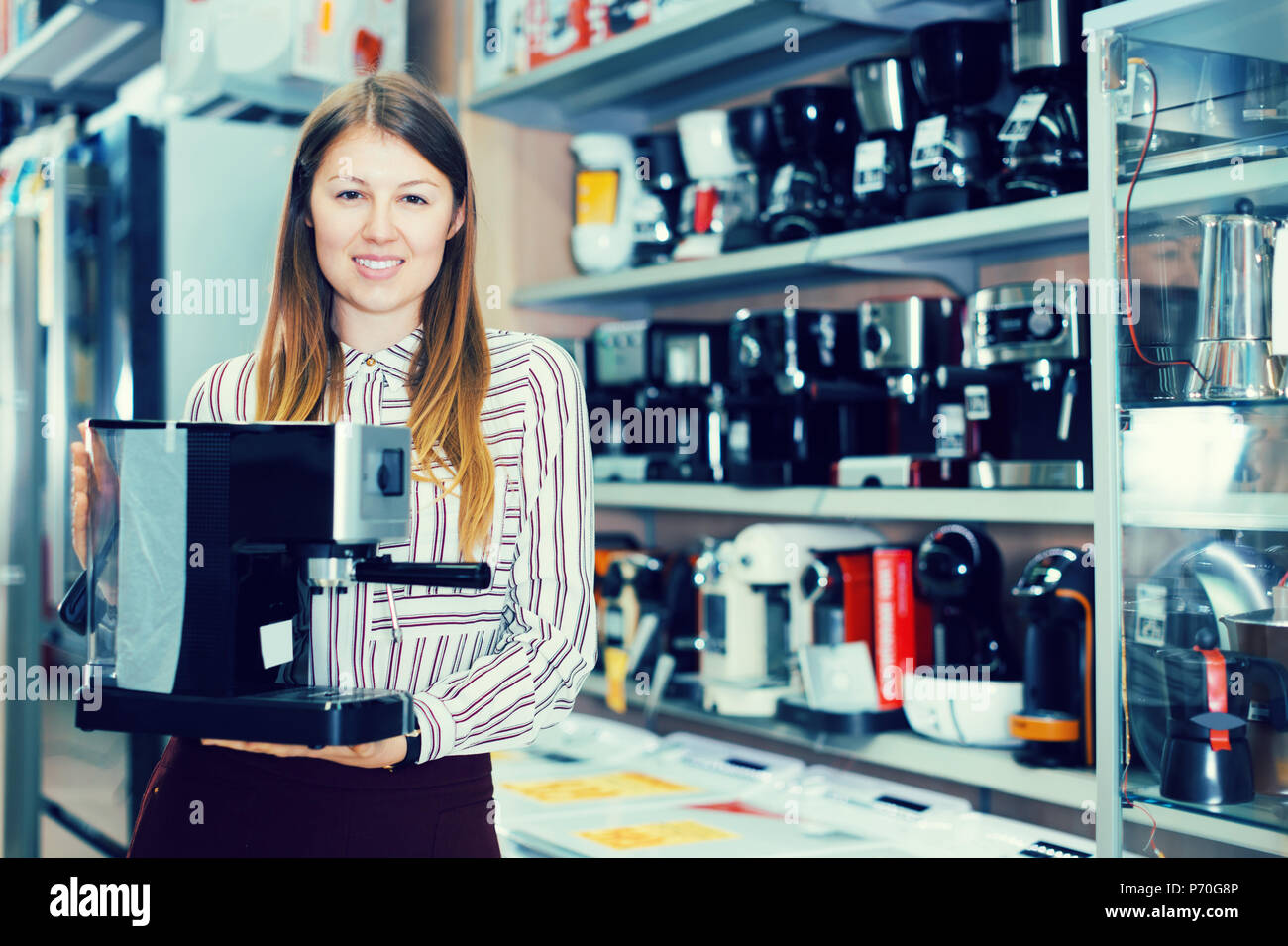 Jeune vendeuse suggérant une machine à café dans la boutique Banque D'Images