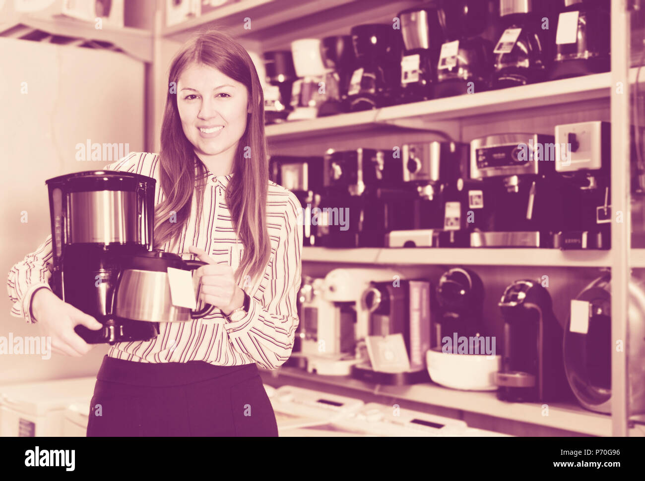Smiling saleswoman offrant infuseur à café dans le magasin d'appareils de cuisine Banque D'Images