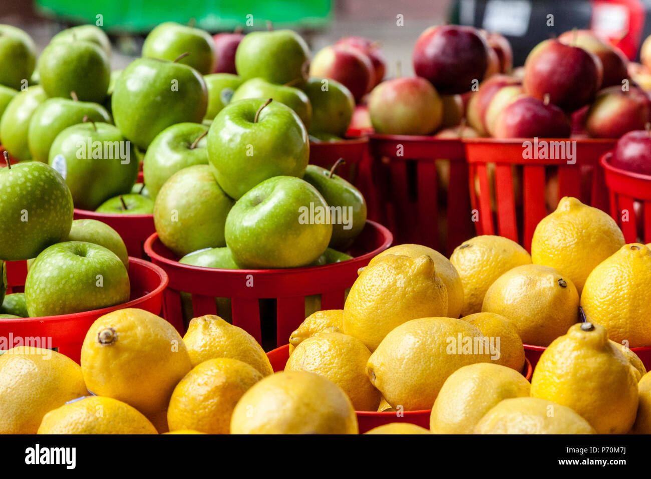 Les citrons dans un panier avec des pommes vertes et rouges à l'arrière-plan. Banque D'Images