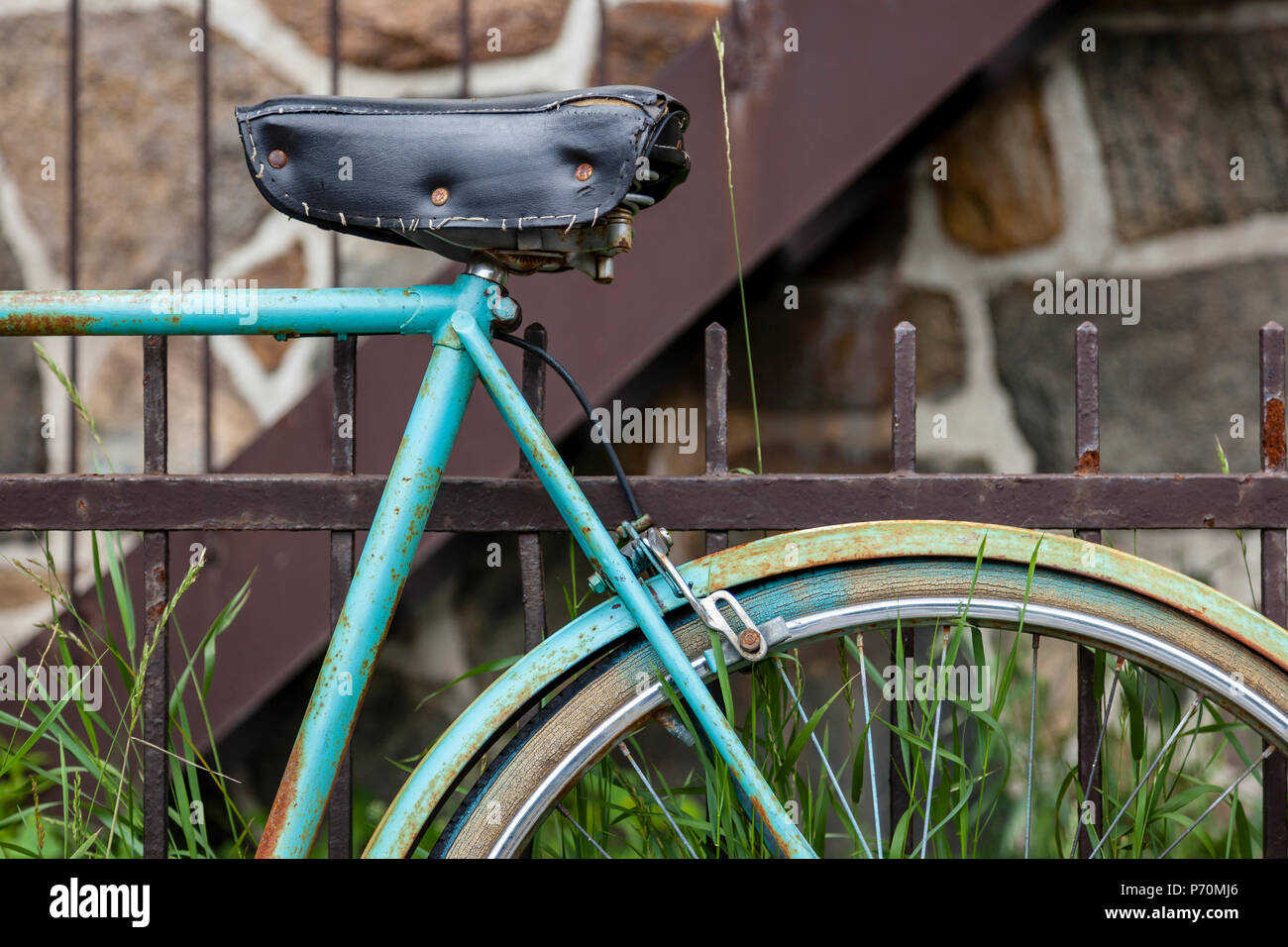 Libre d'une roue de vélo et le siège s'appuyant sur une clôture rouillée. Banque D'Images