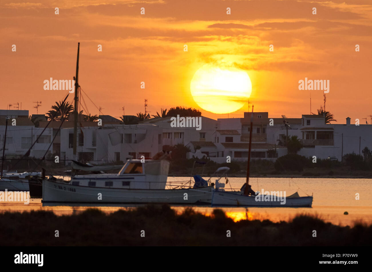 Bateau traditionnel, llaüt, et d'autres bateaux dans la lagune marine Estany des Peix avec le lever du soleil dans le Parc Naturel de Ses Salines, Formentera (Baléares) Banque D'Images