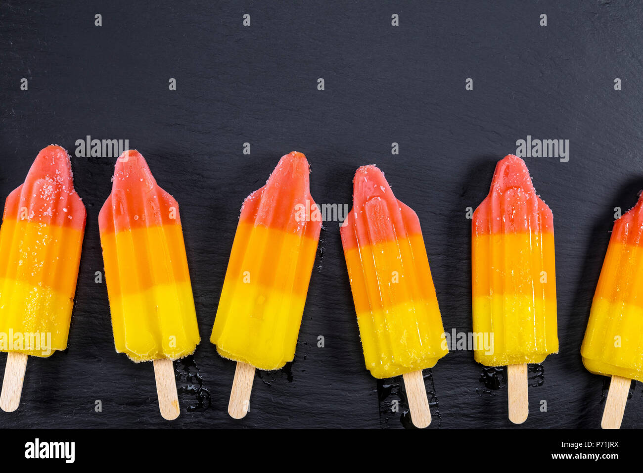 Lime et orange ice cream on stick sur l'ardoise noire. Se concentrer sur les sucettes glacées. Banque D'Images