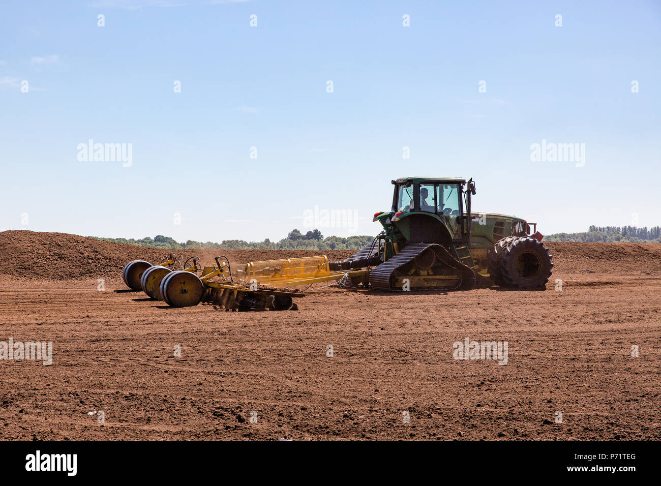 Tracteur agricole tirant le Miller au domaine de la tourbe prospère dans le comté de Kildare, Irlande. Banque D'Images