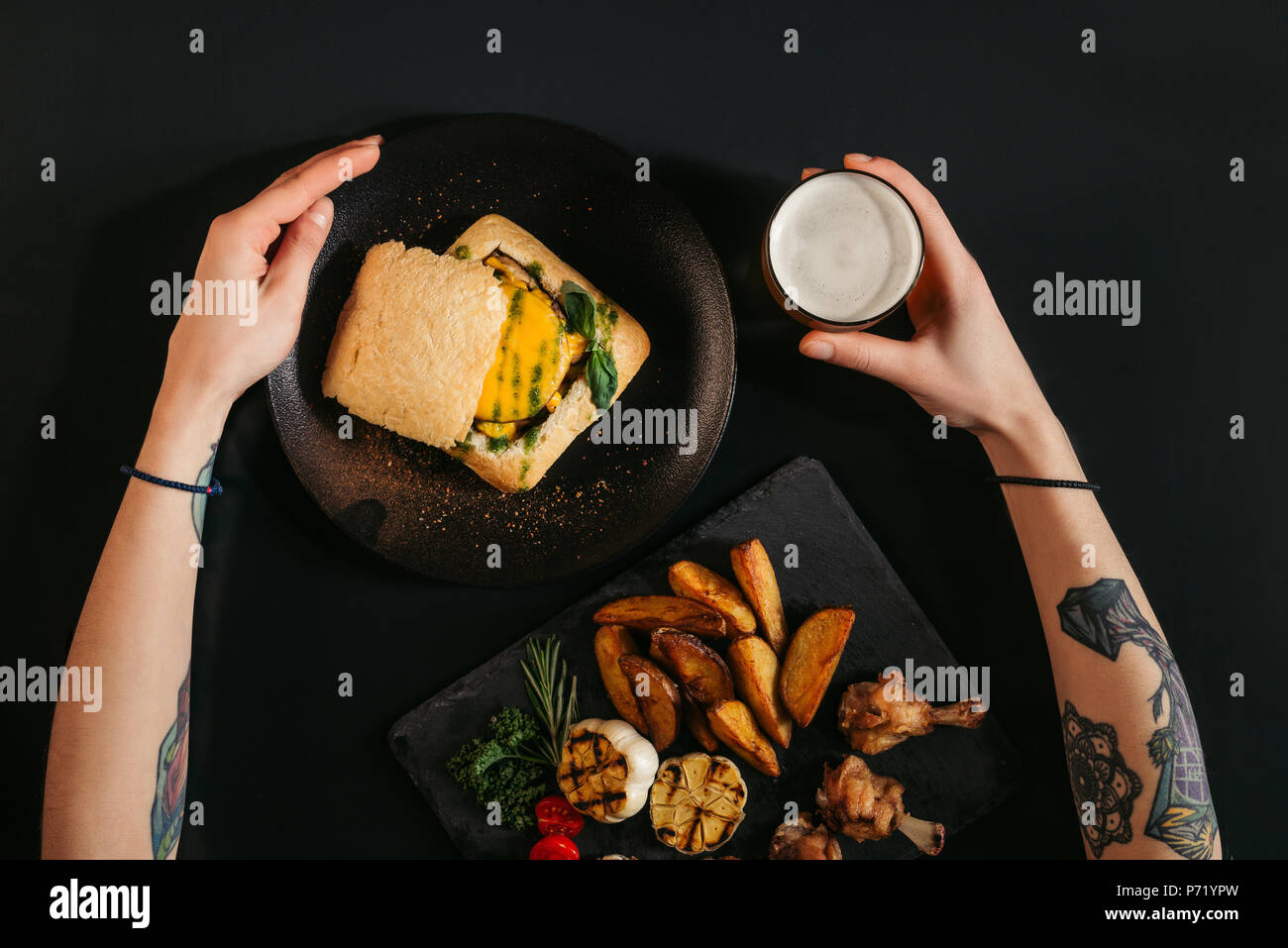 Vue de dessus de personne mangeant végétalien délicieux burger avec frites et boire de la bière sur noir Banque D'Images