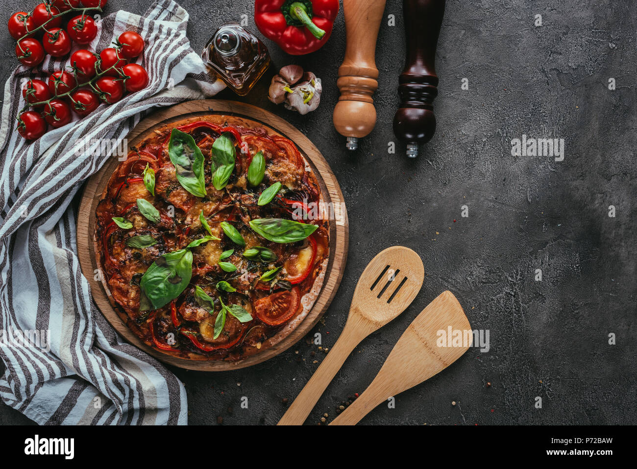 Vue de dessus de la pizza avec des spatules en bois sur table béton Banque D'Images