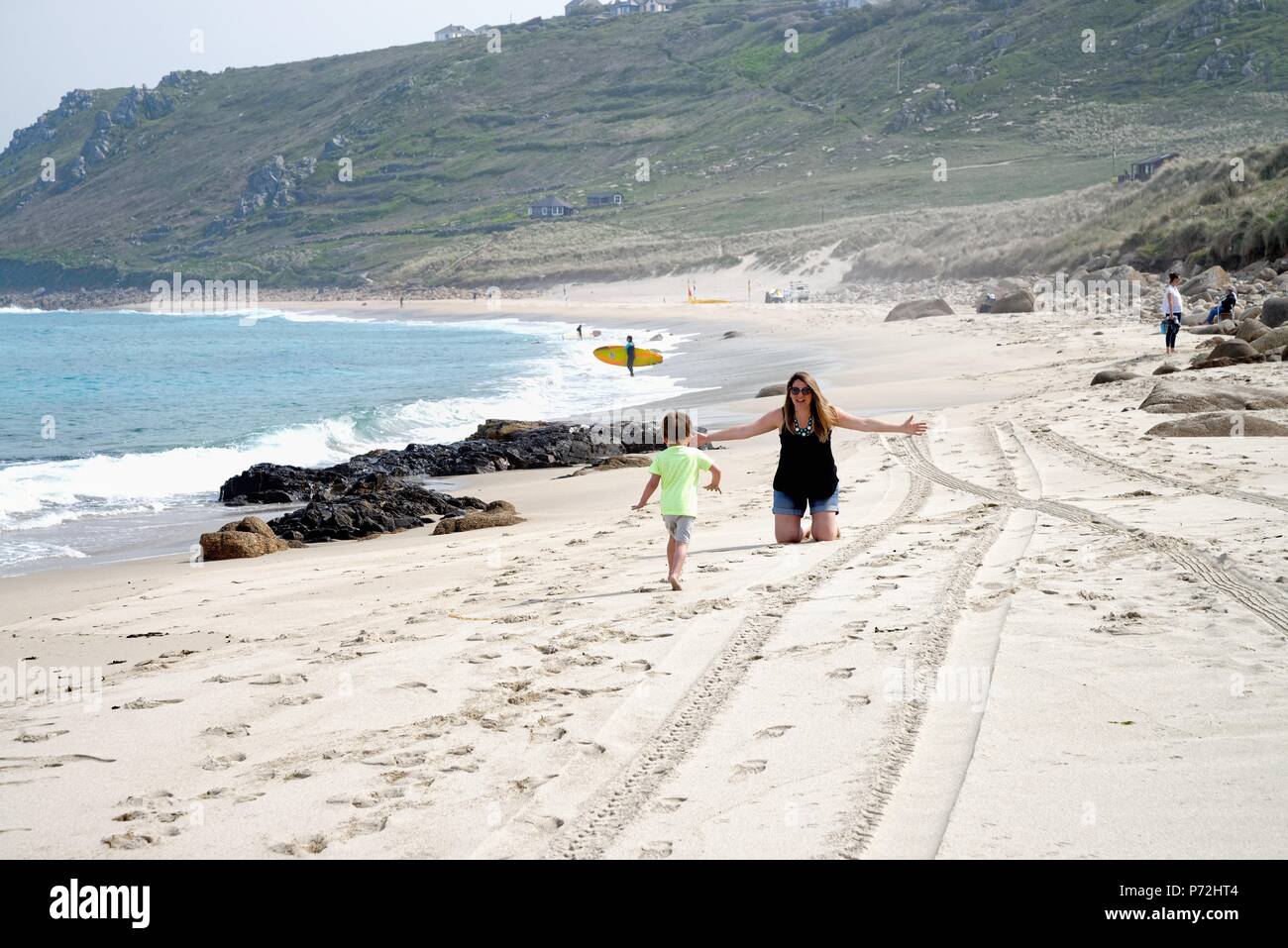 Petit garçon courir vers sa mère qui a les bras grands ouverts prêt à l'étreindre, sur la plage de Sennen Cove sur un été, Cornwall England UK Banque D'Images