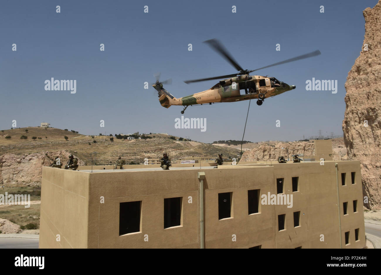 Les forces d'opérations spéciales italiennes, U.S. Air Force Special Tactics et membres de la Forces armées jordaniennes d'étude spécial de corde rapide un Royal Jordanian Air Force UH-60L hélicoptère Blackhawk sur un édifice de trois étages au cours de l'exercice lion avide 11 mai 2017, le Roi Abdullah II Centre de formation d'opérations spéciales. Lion avide est un exercice annuel le Commandement central américain en Jordanie visant à renforcer les relations militaires entre les Etats-Unis, la Jordanie et d'autres partenaires internationaux. La nouvelle édition se compose d'environ 7 200 militaires provenant de plus de 20 nations t Banque D'Images