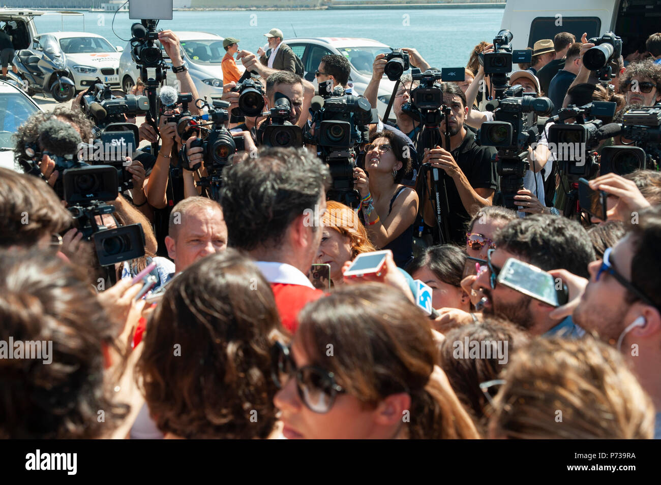 Barcelone. Le 04 juillet, 2018. Un membre de la Croix-Rouge explique aux médias les conditions dans lesquelles les immigrants sont arrivés à bord du navire voiles les bras ouverts. Le bateau a navigué jusqu'à l'aide humanitaire Espagne avec 60 immigrants de 14 nationalités ont sauvé le samedi dans les eaux près de la Libye, après qu'il a été rejeté par l'Italie et Malte. Banque D'Images