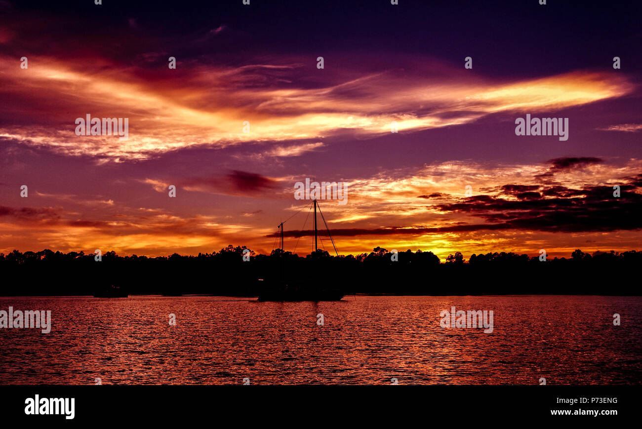 Une spectaculaire orange de couleur vive nuageux soleil panoramique tropical seascape avec de l'eau de l'océan avec des silhouettes reflecions. L'Australie. Banque D'Images