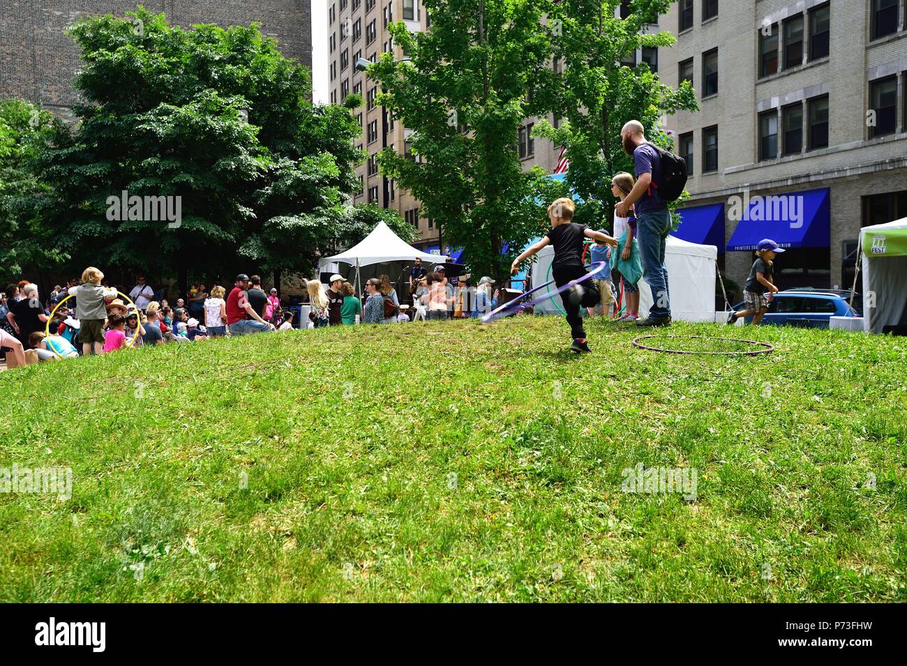 Chicago, Illinois, USA. Les enfants jouent avec des cerceaux comme d'autres prennent dans un concert dans un petit parc dans le cadre de la ligne d'imprimantes allumé Fest. Banque D'Images