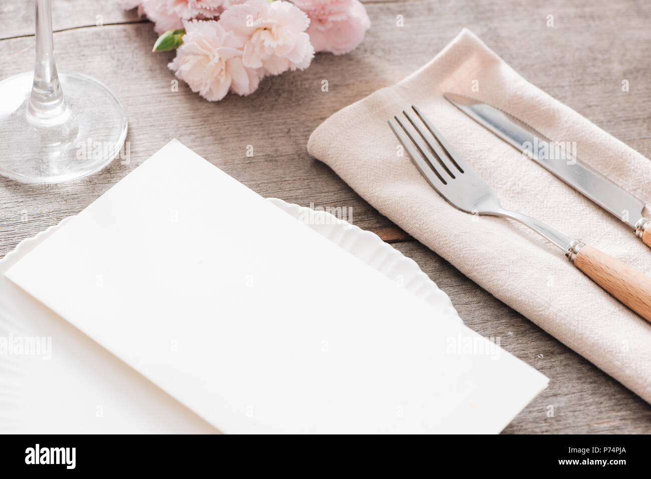 Décoration de table avec des fleurs de printemps. Les plaques blanches, fourchette, couteau sur plaque de bois Banque D'Images
