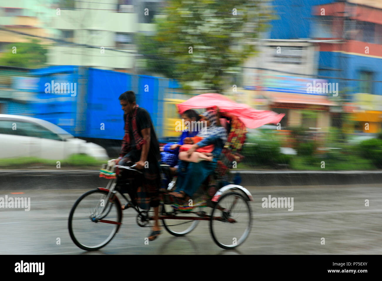 Un rickshaw puller porte ses passagers dans le jour de pluie, Dhaka, Bangladesh. Banque D'Images