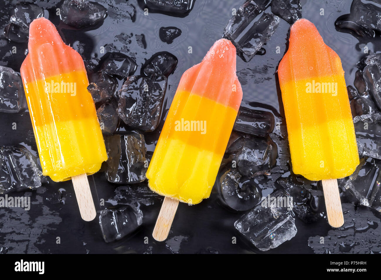 La crème glacée aux fruits sur stick sur glace sur l'ardoise noire. Se concentrer sur les sucettes glacées. Banque D'Images
