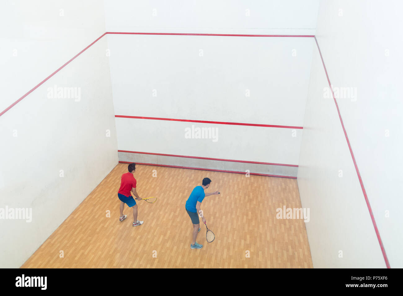 Vue arrière de la concurrence de deux jeunes hommes jouant le jeu de squash Banque D'Images