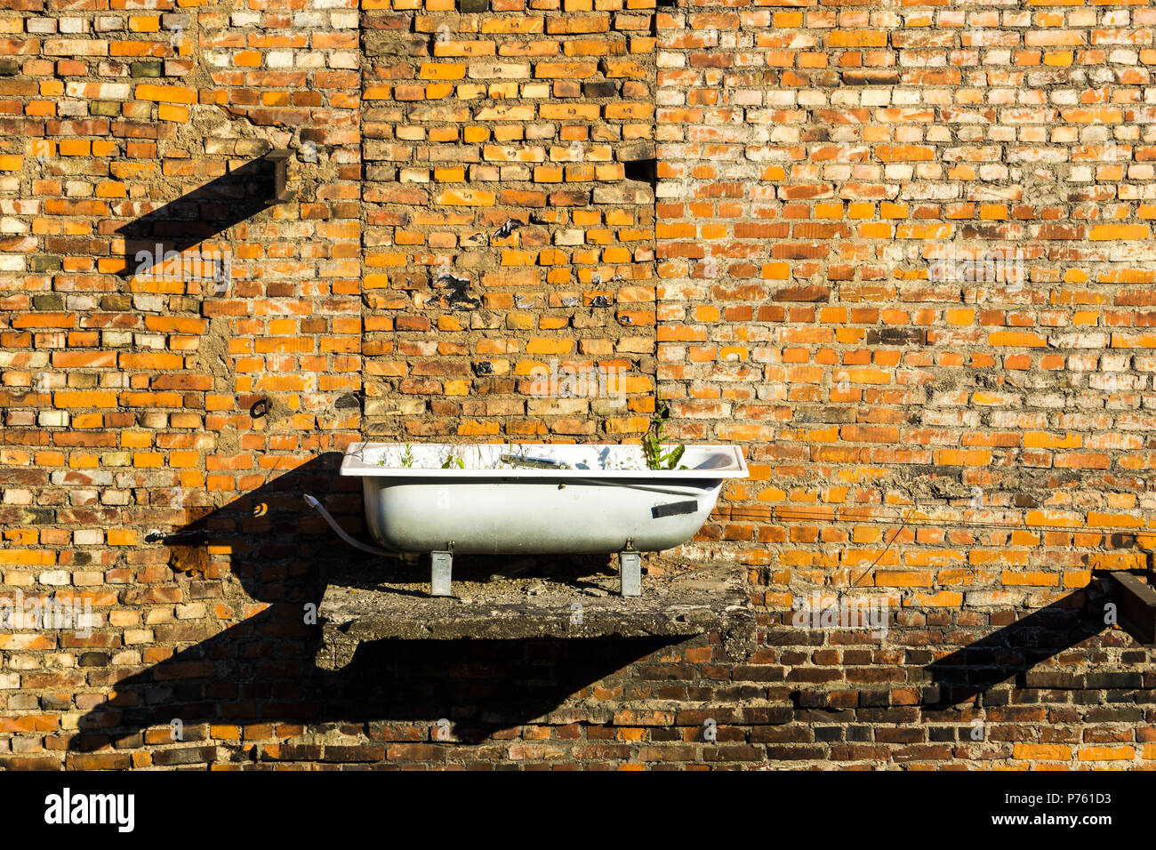 Mur de brique en pierre rouge avec baignoire utilisé comme pot de fleurs Banque D'Images