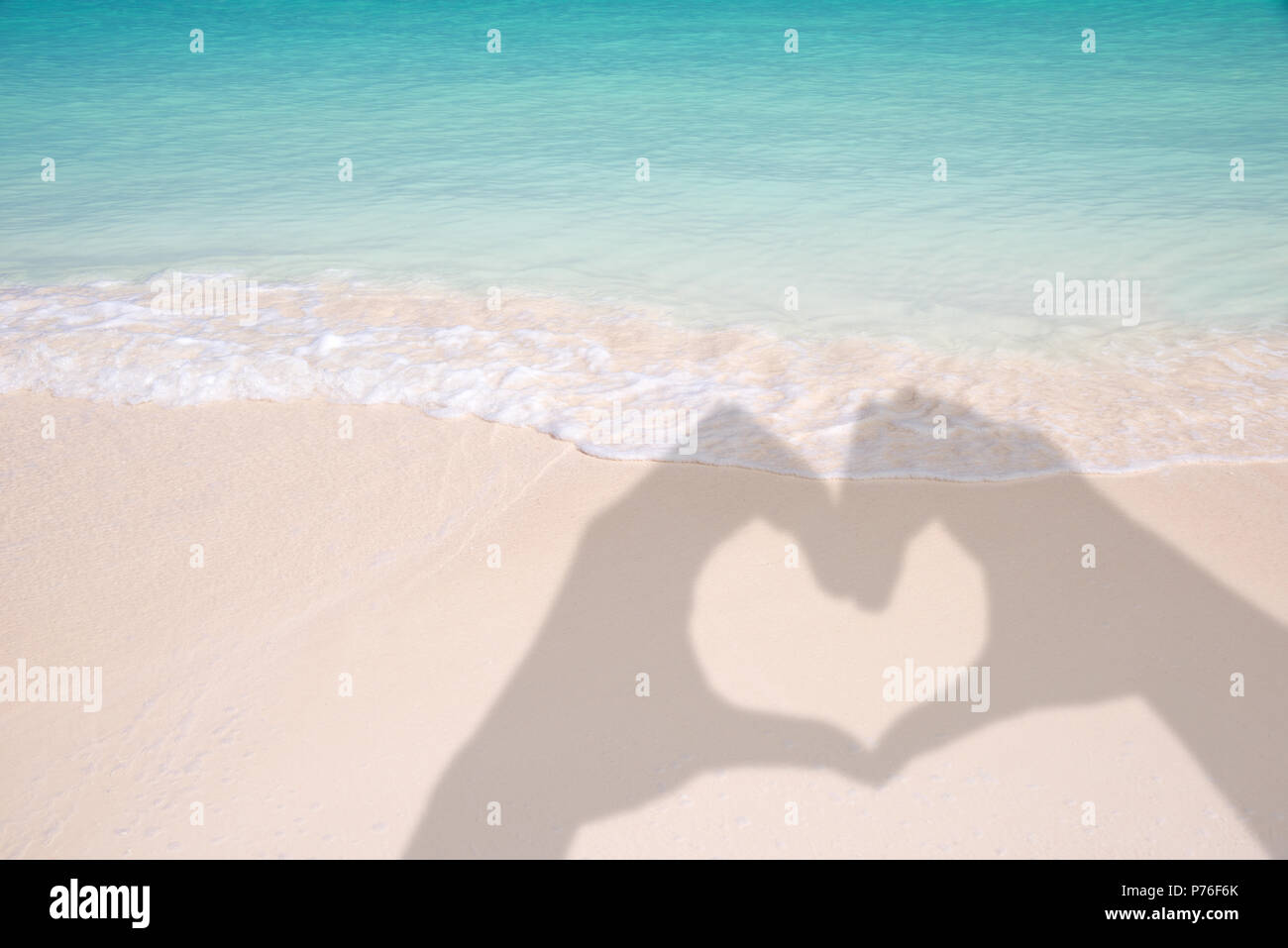 Ombres de mains formant un coeur sur fond de plage de sable et des Caraïbes Banque D'Images