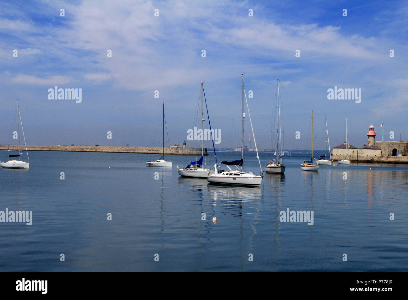 Port de Dun Laoghaire avec des yachts amarrés en premier plan et les cheminées de l'ancienne centrale de Poolbeg en arrière-plan. Banque D'Images