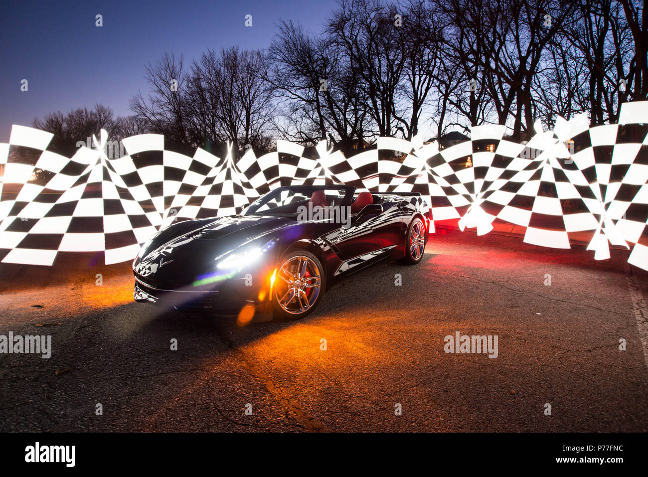 Corvette C7 noir sur l'affichage la nuit avec motif à damiers autour d'elle. Banque D'Images