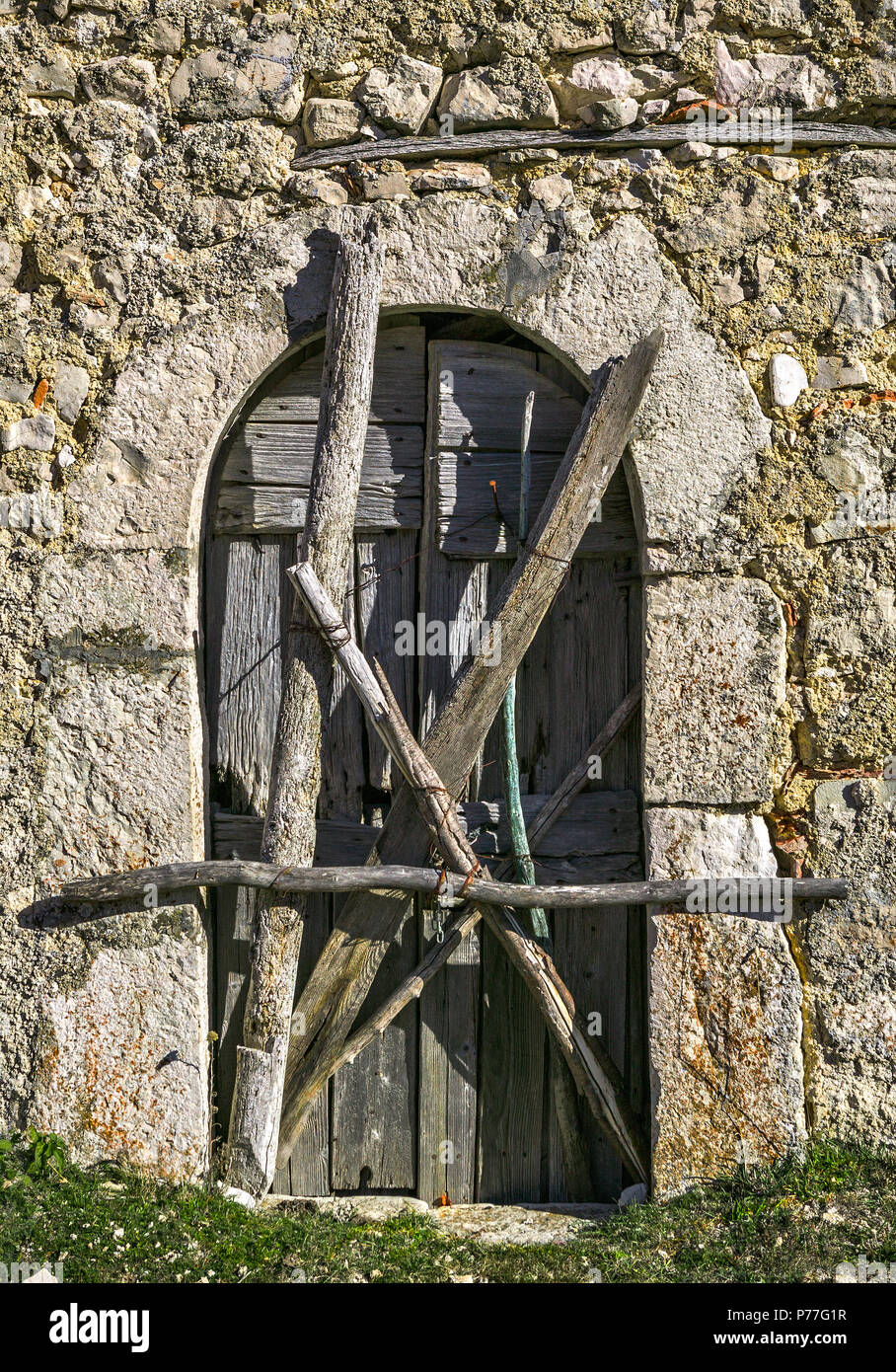 Façade d'une ancienne maison en pierre avec une porte en bois barrée d'un enchevêtrement de poteaux.Abruzzes, Italie Banque D'Images