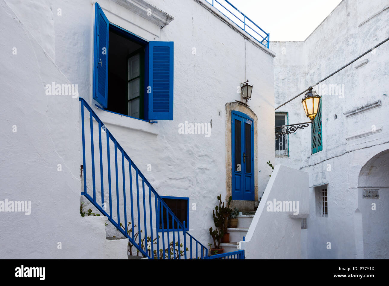 Ostuni, ITALIE - 11 août 2017 : vue sur une rue étroite avec une porte bleue et fenêtre bleu dans la romantique vieille ville d'Ostuni (Pouilles, Italie), un Banque D'Images