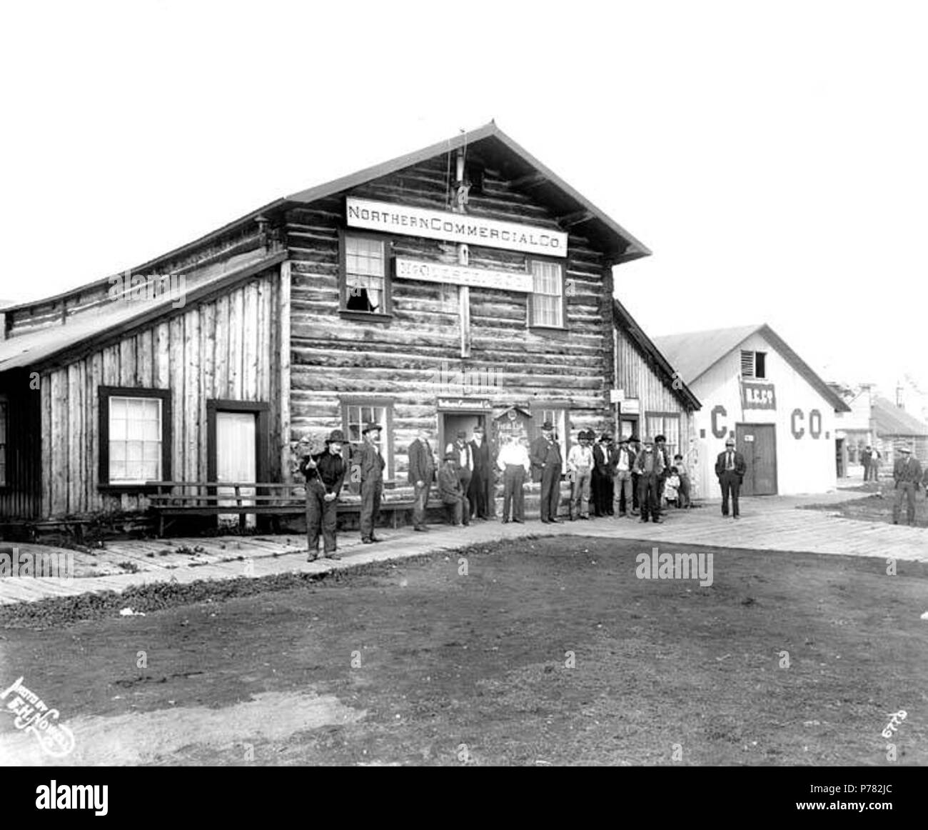 . Anglais : les gens en face de vous connecter avec des panneaux pour le Nord de Co. et McQuesten & Co., Cercle, ca. 1905 . Anglais : Légende sur l'image : Photo par F.H. Nowell, 6779 au verso de l'image : Northern Commercial Co. Bldg., Circle City, Alaska Cercle est situé sur la rive gauche du fleuve Yukon, à 130 milles au nord-est de Fairbanks. C'était une ville de l'approvisionnement minier établi en 1887 quand L.N. McQuesten situé à un poste de traite à cet endroit. Il a été ainsi nommée parce que le village a été pensé pour être sur le cercle arctique. La population était de 41 en 1967. (Page 18) 219) Note de Donald Orth, Dictionnaire de l'Alaska Place Banque D'Images
