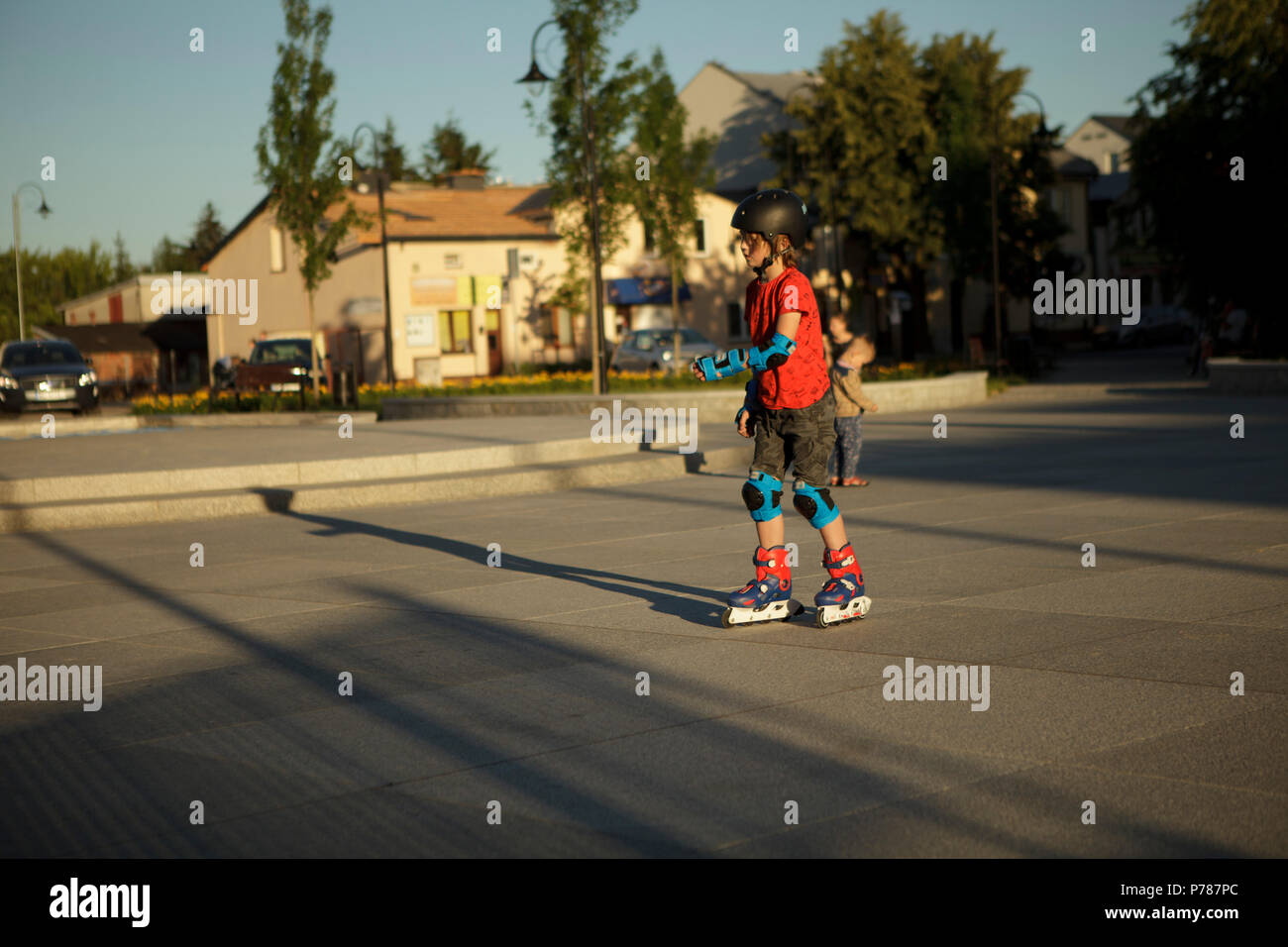 Garçon ridinig sur rollerskates sur city square, l'été, le soir Banque D'Images
