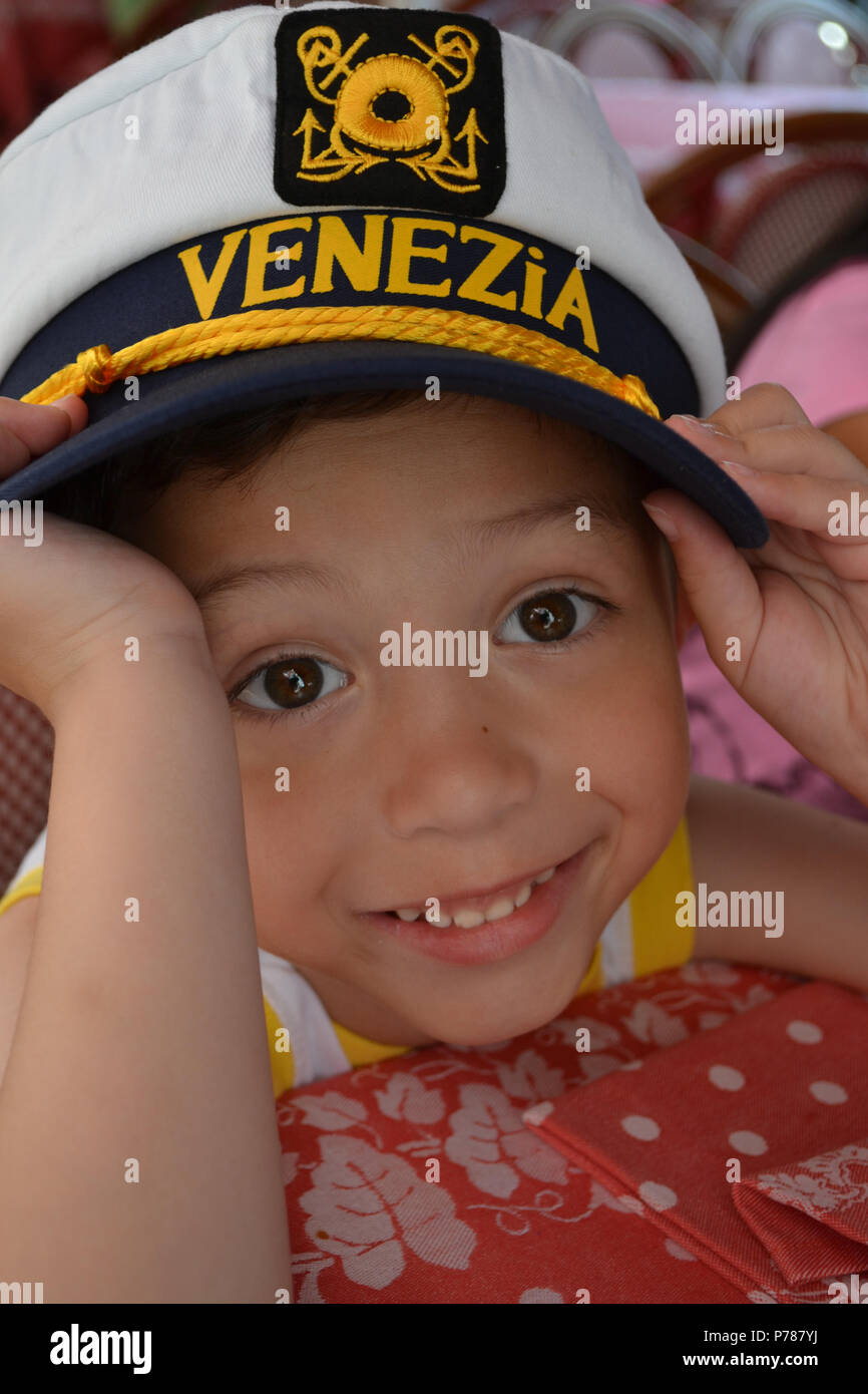 Smiling boy portant un grand chapeau de marin avec le mot "Venise" brodé sur l'avant. Banque D'Images