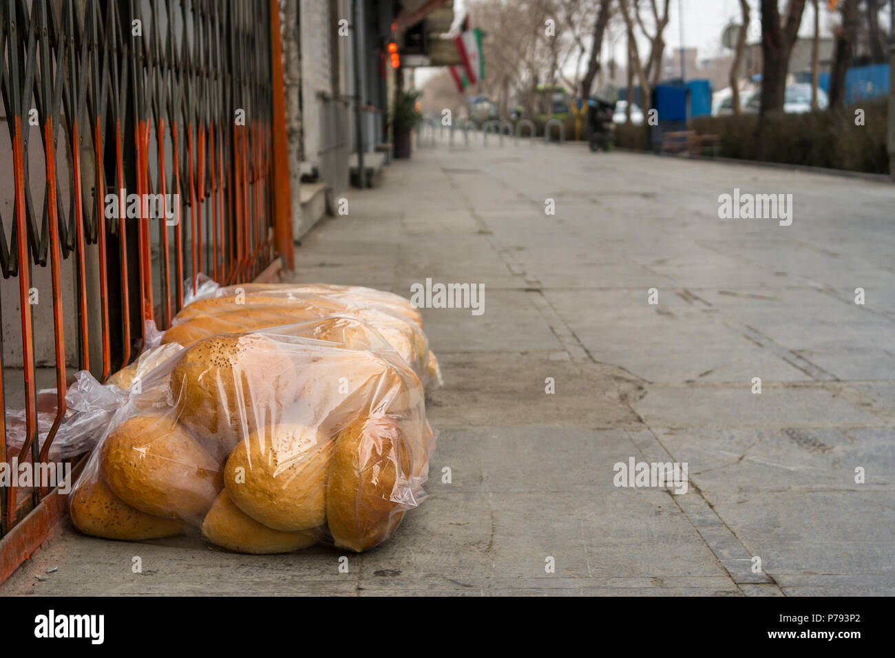Une livraison de pains fraîchement cuits dans des sacs de plastique mise sur le trottoir à l'extérieur d'une boutique d'attente avant d'ouvrir. Banque D'Images