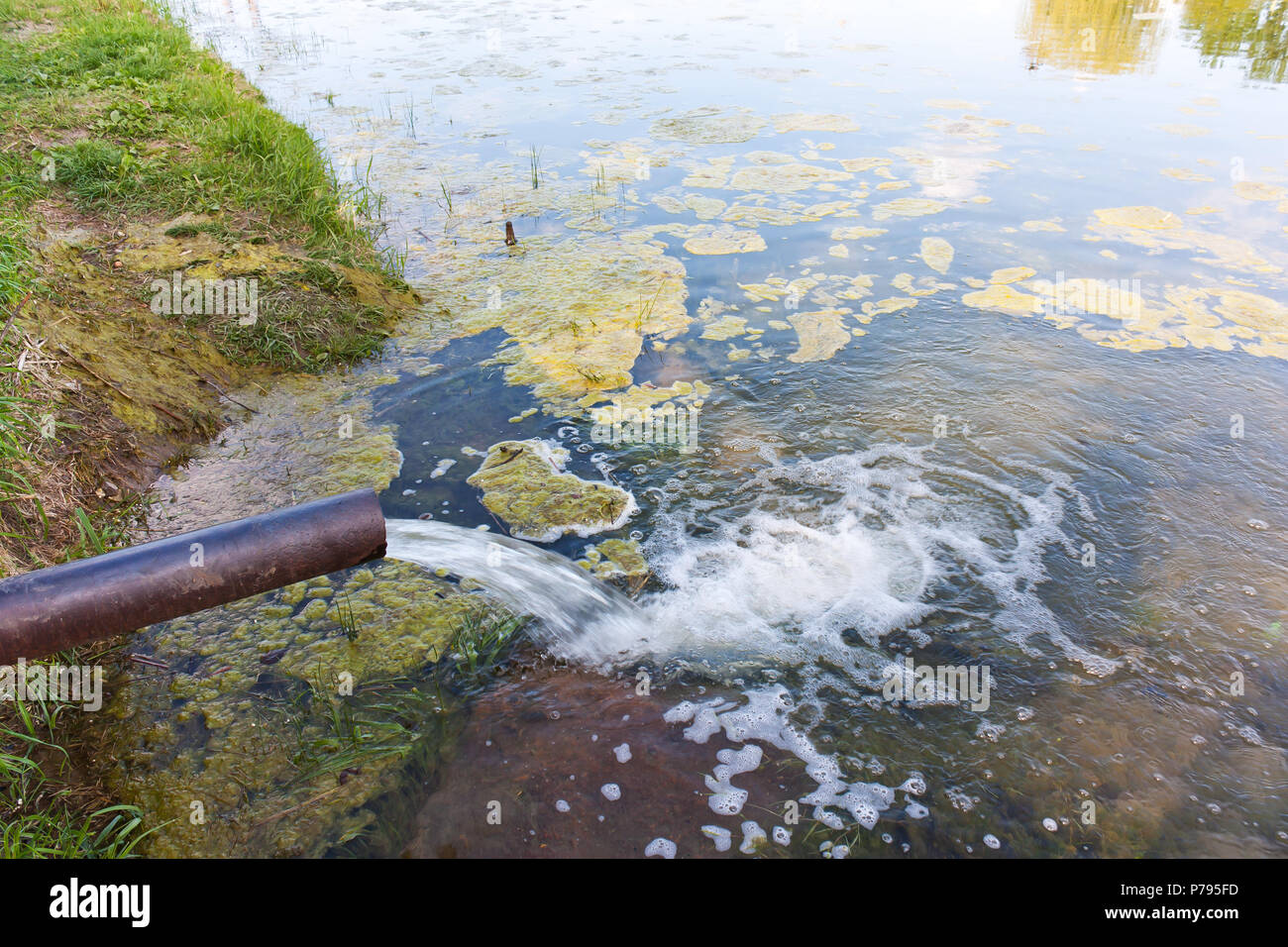 Sur le tuyau l'eau s'écoule dans la rivière, le lac, la mer. La pollution de l'environnement, catastrophes écologiques Banque D'Images