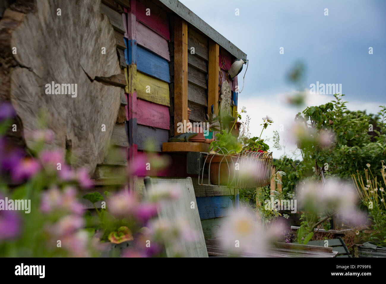 Un beau hangar décoré peint à rayures pastel situé dans un jardin paisible. Banque D'Images