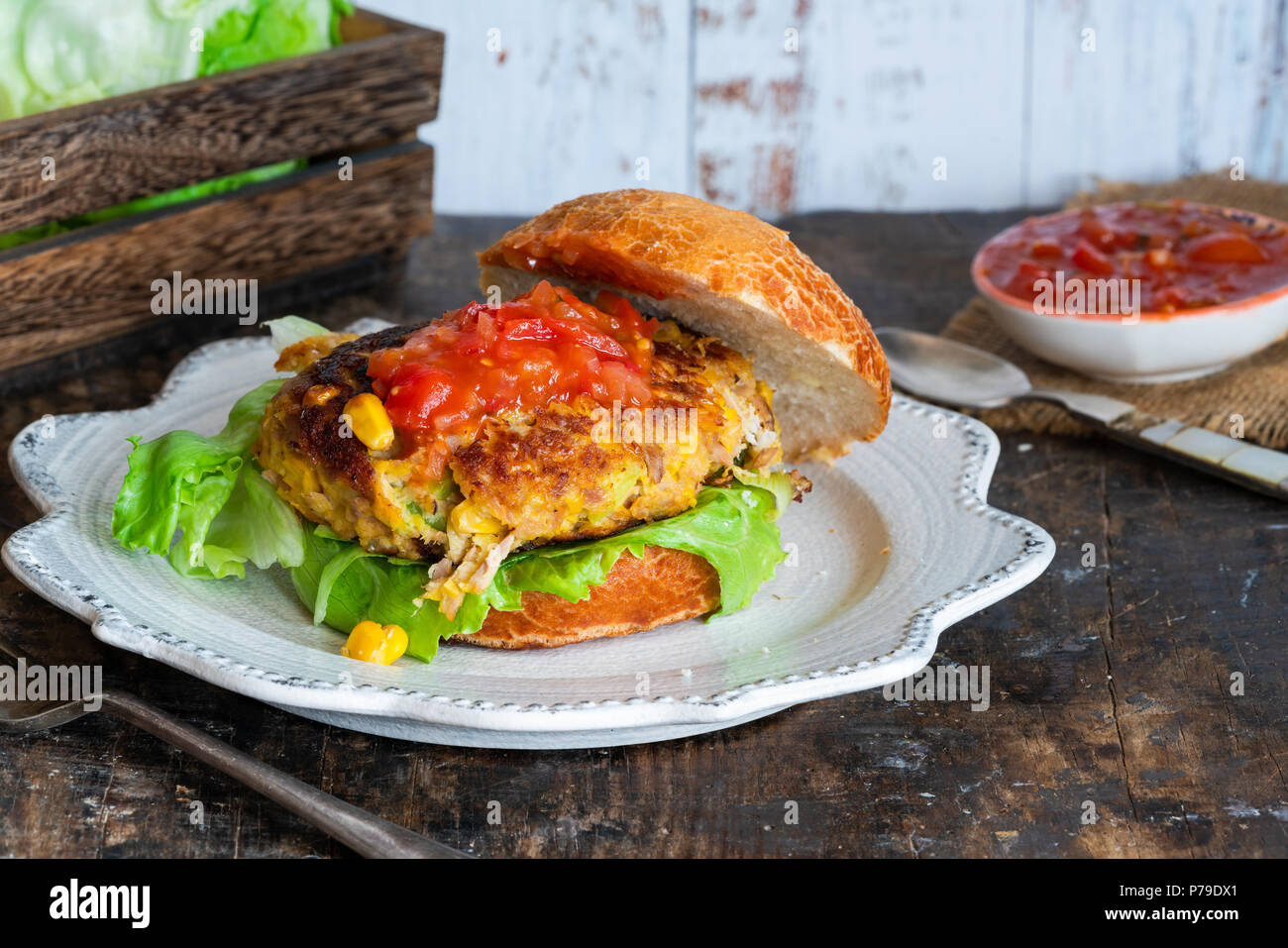 Le thon et le maïs burger avec salsa de tomates dans un petit pain Banque D'Images