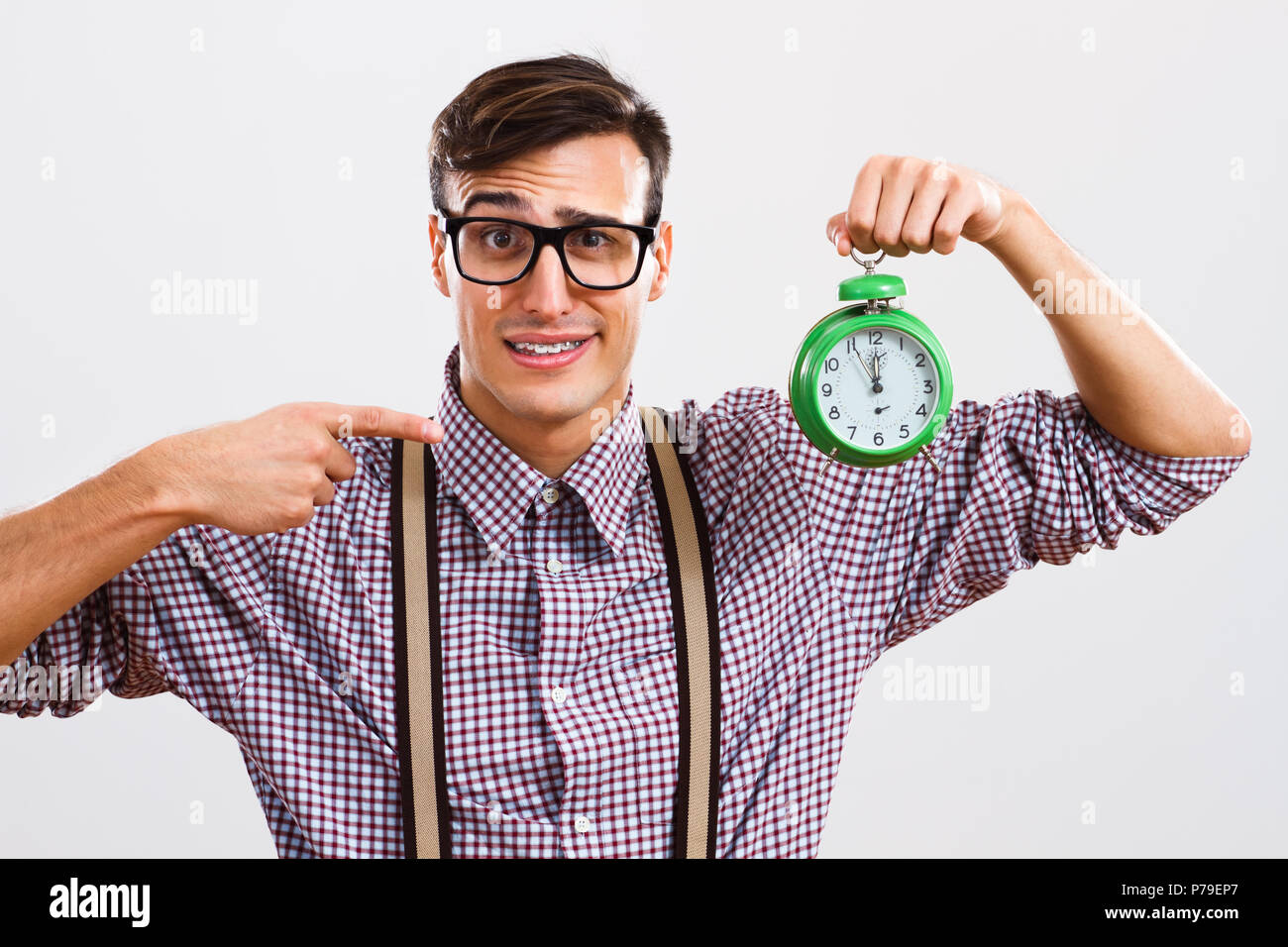 Nerdy homme pointant à l'horloge. Banque D'Images