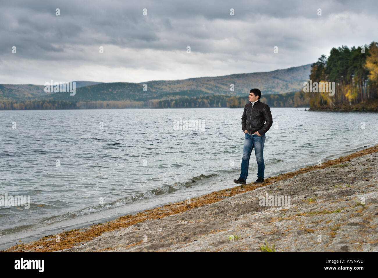 Jeune homme outdoor le mouillage de l'eau pour bateau, temps couvert froid en automne Banque D'Images