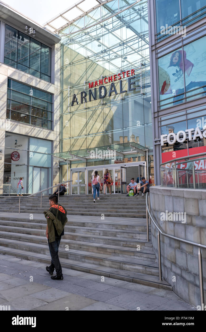 Un jeune homme marche devant l'entrée de la Manchester Arndale Centre. Manchester, UK Banque D'Images
