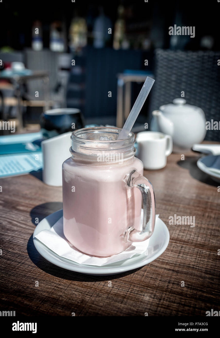 Strawberry milkshake boire dans un grand verre inhabituelle avec une poignée Banque D'Images