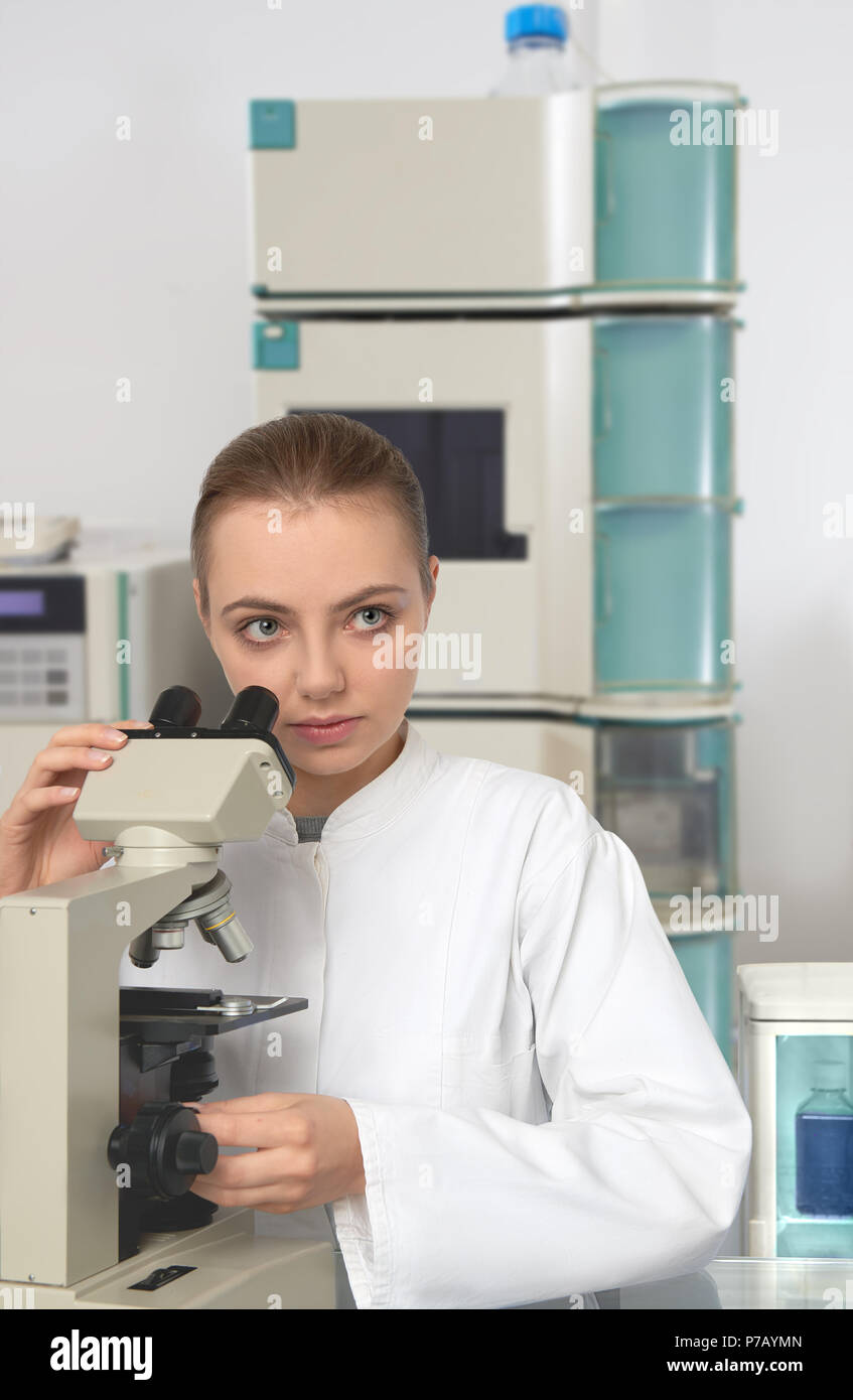 Young female scientist in white blouse de laboratoire travaillant avec un microscope dans un laboratoire moderne Banque D'Images