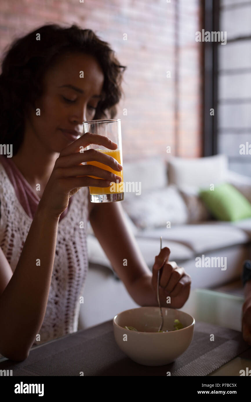 Femme ayant le jus d'orange avec petit déjeuner Banque D'Images