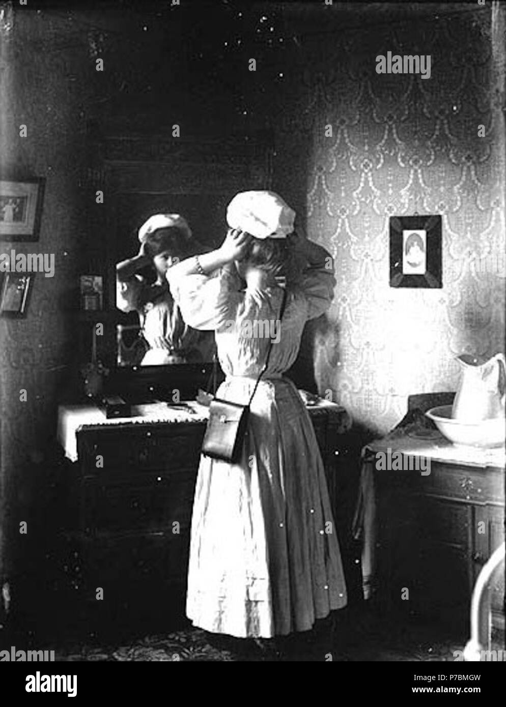 . Anglais : Unidentified man hat in front of mirror, Washington, ca. 1913 . Anglais : Peut-être Peut Toyne Barnes, épouse de A.H. Barnes. Sur le manchon de négatif : Portrait Femme au miroir Sujets (LCTGM) : Les femmes--et--Vêtements Robe de Washington (État) ; Boudoirs--Washington (État) ; Chapeaux ; Miroirs Sujets (LCSH) : Barnes, mai Toyne . vers 1913 81 une femme non identifiée essayant sur hat in front of mirror, Washington, ca 1913 (153 bar) Banque D'Images