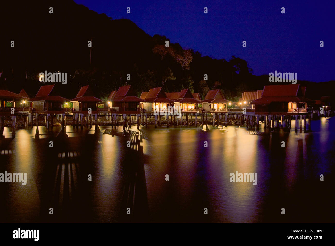 Chalets de style malaisien surélevés sur pilotis dispersés à travers la mer, le Berjaya Langkawi Resort de nuit est une véritable évasion tropicale. Pris dans... Banque D'Images