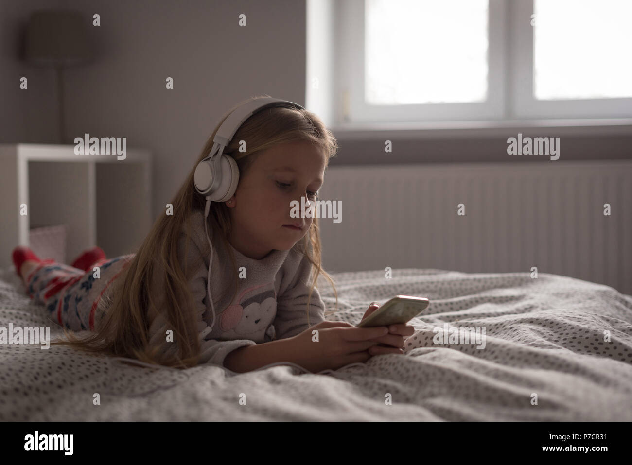 Girl listening music sur téléphone mobile avec un casque dans la chambre Banque D'Images