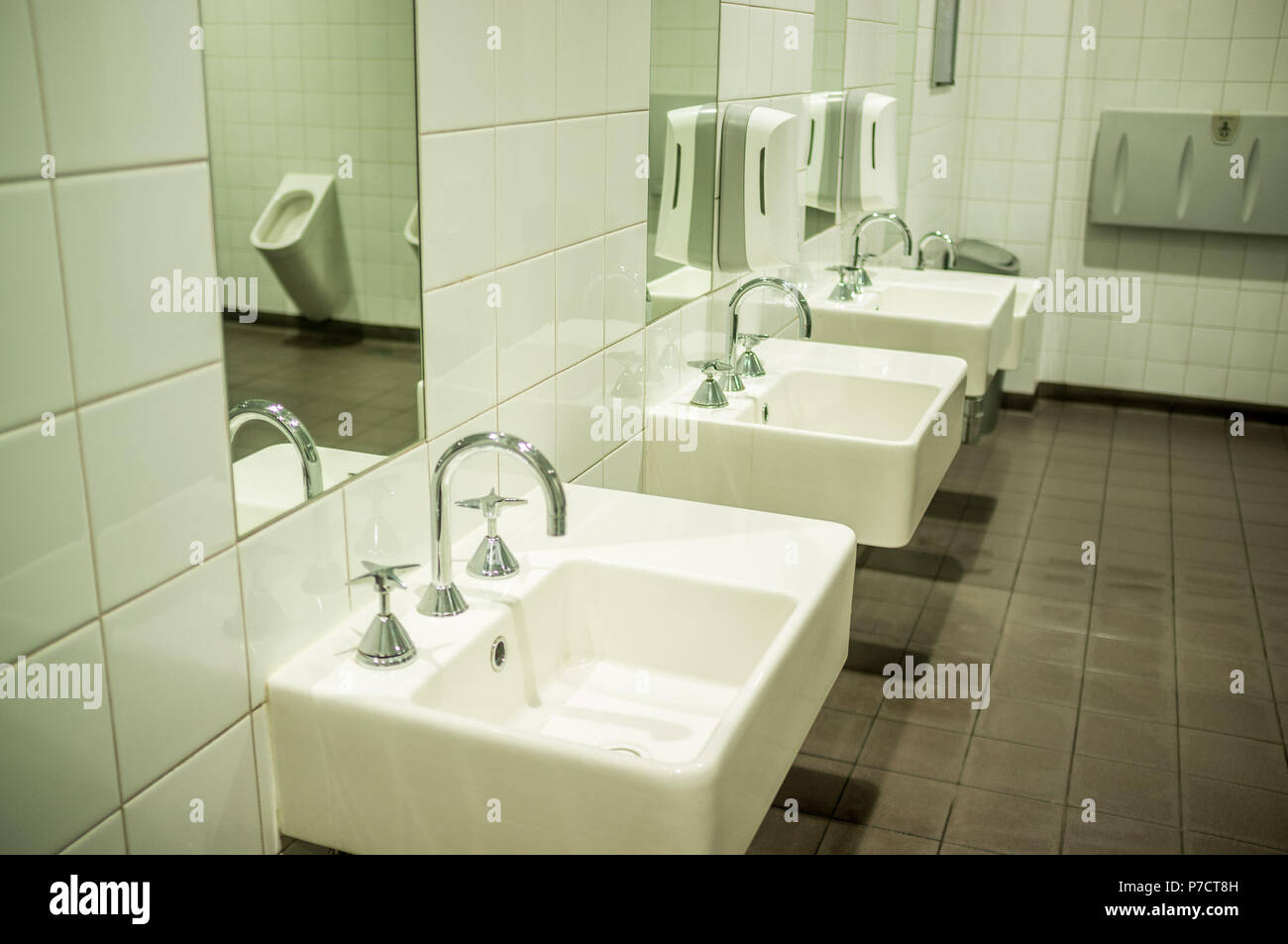 Hommes en blanc avec toilettes et lavabos élégant miroir en reflétant l'urinoir Banque D'Images