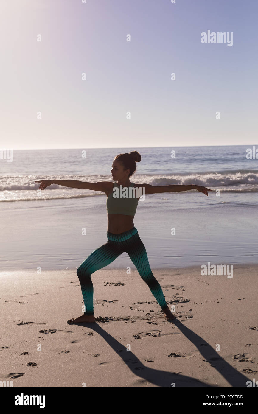 Fit woman performing exercice s'étendant dans la plage Banque D'Images