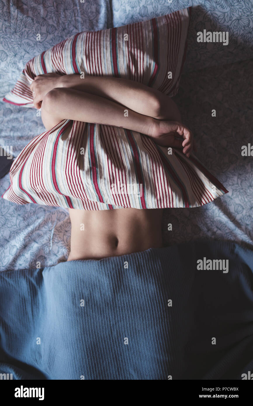 Woman embracing oreiller tout en dormant dans la chambre Banque D'Images